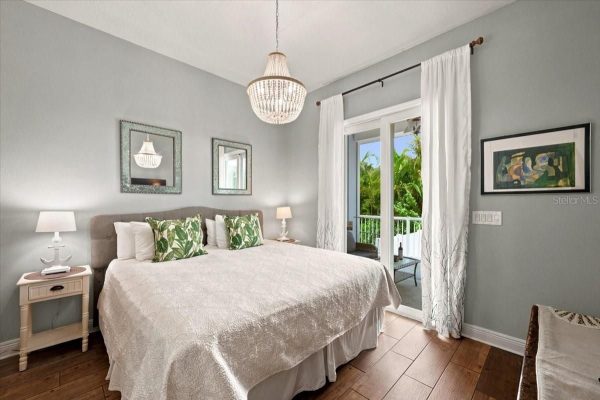 Bedroom with a king bed, white textured quilt, and tropical-green throw pillows flanked by matching nightstands and lamps on each side.