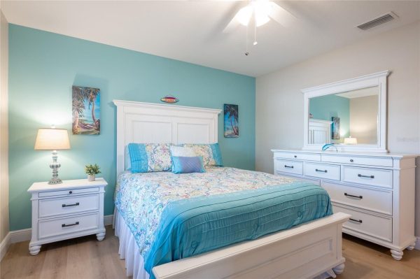 Coastal bedroom with teal accent wall, white bed frame, turquoise quilt, and matching dresser and nightstands.