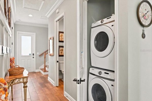 Hallway with a stacked washer and dryer in a closet on the right; front door at the end of the hall.