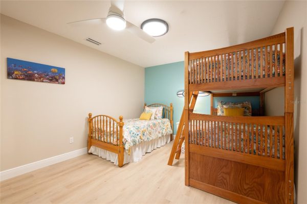 Children's bedroom with a wooden bunk bed and a single bed, pastel teal accent wall, and ocean-themed bedding