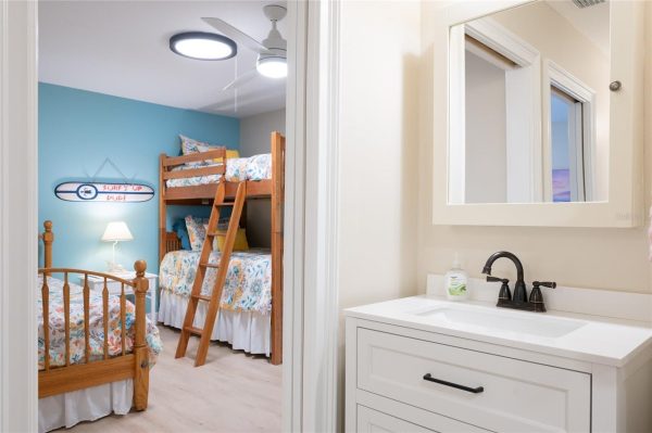 Bedroom with teal feature wall, wooden bunk beds, and a ladder leading to the top bunk with floral bedding.