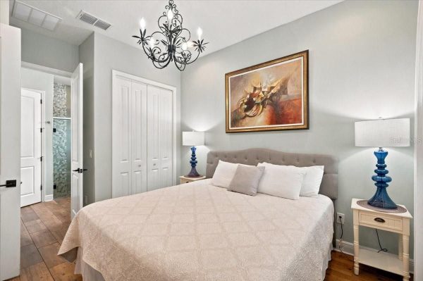 King-size bed with a tufted gray headboard, beige quilt, and two blue glass lamps on white nightstands.