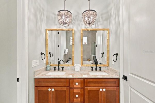 Double-sink bathroom vanity with two mirrors, woven bamboo frames, and pendant lights overhead