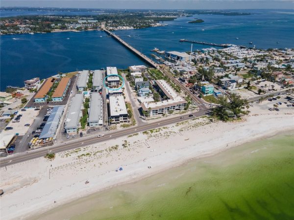 Aerial view of a coastal neighborhood with a blue-circled three-story building near the beach.
