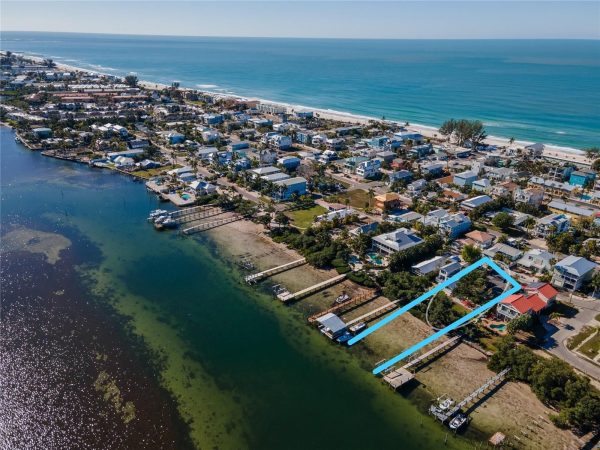 Aerial view of a coastal town with ocean to the right and a highlighted rectangular waterfront lot outlined in light blue near the shore.