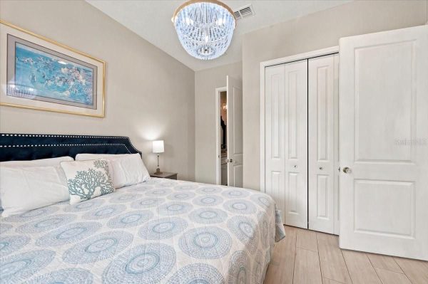 Bedroom with a queen bed, navy upholstered headboard, patterned blue sheets, and a nightstand lamp beside it.