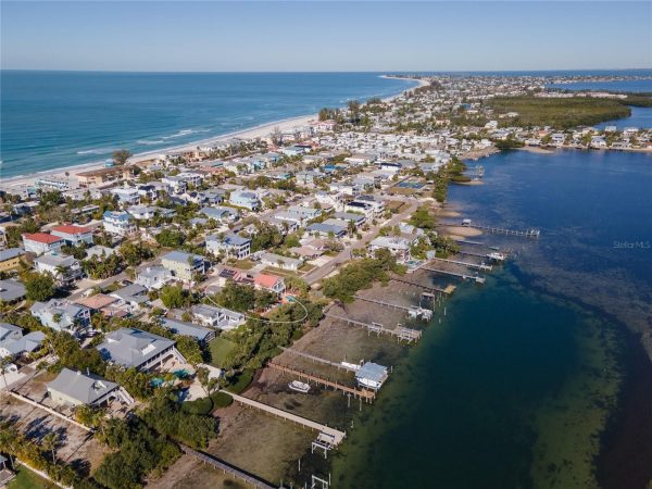 Aerial view of a coastal town along a sandy beach, with houses and canals on the water coast.