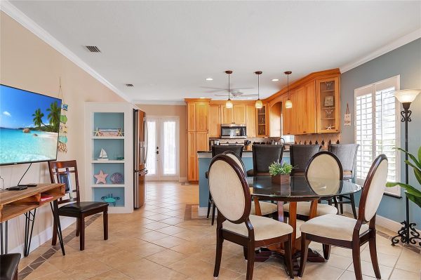 Bright open-concept kitchen and dining area with wooden cabinets, pendant lights, and a round glass table