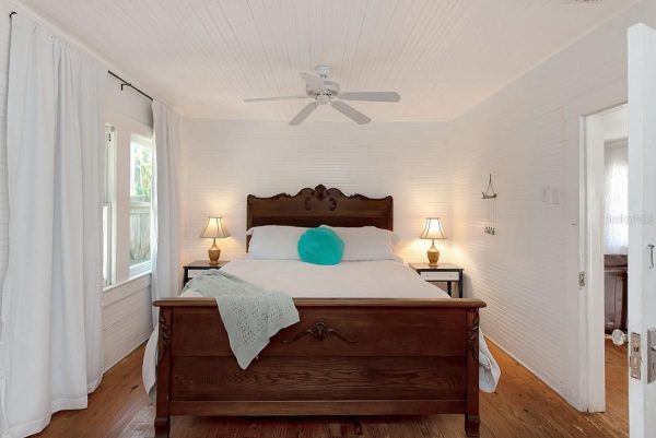 Bedroom with a carved dark wood bed, white bedding, turquoise heart pillow, and two nightstand lamps.